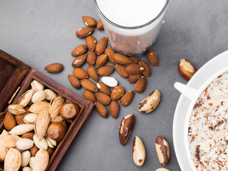 Vegan milk from nuts in glass jar with various nuts on concrete background
