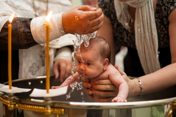 Newborn baby baptism in Holy water. baby holding mother's hands. Infant bathe in water. Baptism in...