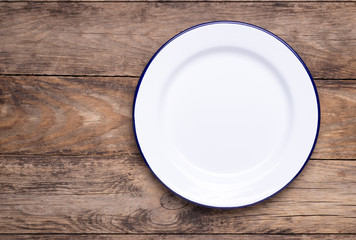 Empty white plate on old wooden table, top view with copy space	