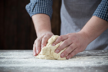 Obraz na płótnie Canvas hands cooking dough on dark wooden background
