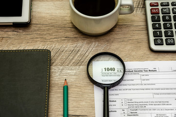 tax form 1040, a magnifying glass. calculator and notebook. View from above.