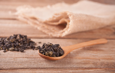 Black dry tea leaves with wooden spoon on the wooden table