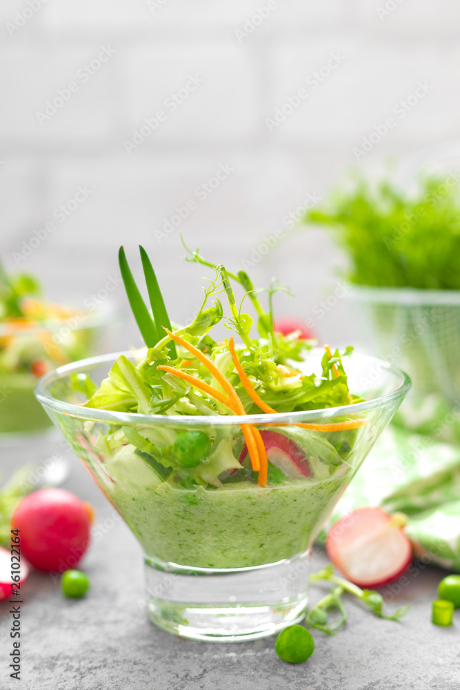 Wall mural Fresh vegan vegetable salad with carrot, lettuce, green peas, radish, sprouts and cucumber smoothie