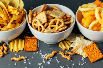 Fototapeta premium Beer snacks on stone table. Various crackers, potato chips. Top view