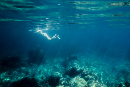 woman swimming in the sea seen from under water