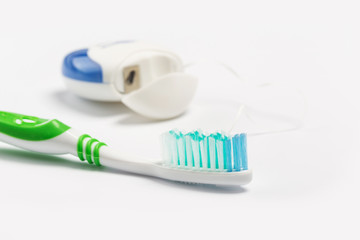 Dental floss and toothbrush isolated on a white background.