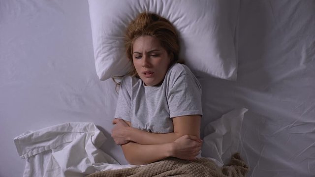 Young woman feeling fever and ache in bones, catching virus and lying in bed