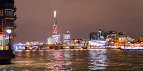London skyline from the Thames river banks. Bright city lights in the dark sky