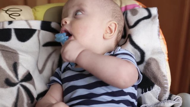 baby boy nibbles a teether toy. the child is sitting on the highchair. face close up