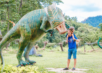 Dad with little daughter near big green dinosaur in the park on a sunny day. Yang Bay, Vietnam