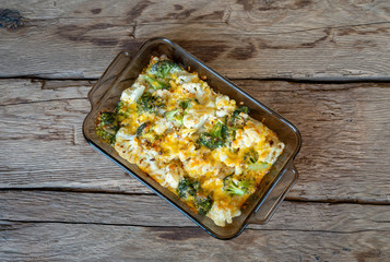 Casserole with cabbage, broccoli and cheese on wood deck.