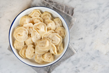 Homemade traditional Russian dumplings on a plate. Marble background, top view