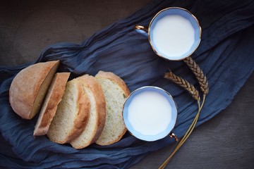 Milk with a blue Cup and sliced bread on a blue napkin.