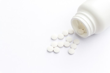 Close up of teblets pills an pill bottle on white background with selective focus