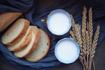 Milk with a blue Cup and sliced bread on a blue napkin.