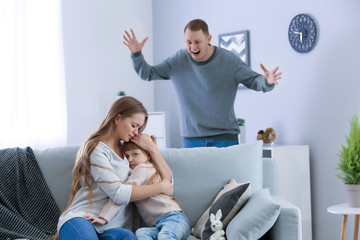 Woman hugging her little daughter during family quarrel