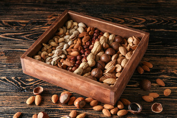 Box with different tasty nuts on wooden table