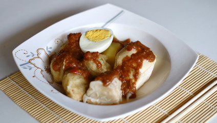 Siomay (fish cake dumplings) and peanut sauce on white background. 