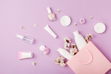 Set of woman's cosmetics in a bag with spring apricot bloom. Women's secrets. Spring female skin and hair care cosmetics in a bag on purple background. Cosmetic with apricot. Shampoo, lotion, tonic