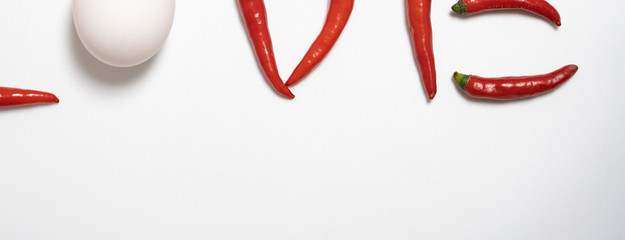 Red chilli isolated in white background with an egg spelling the letter of love