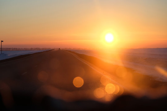 sunset red sun, evening, photo from the car window, traffic on the highway, blurry glare on the glass