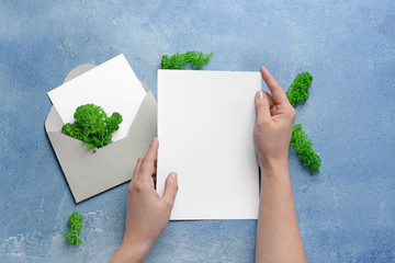 Female hands with invitation on color background
