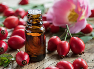 Rose-hips and rose hip seed oil on the wooden table.