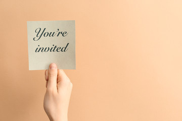 Female hand with invitation on color background