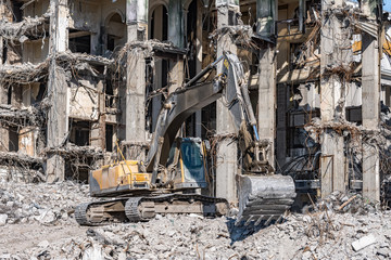 Fototapeta premium Excavator with a digging bucket on the ruins of the house, demolition.