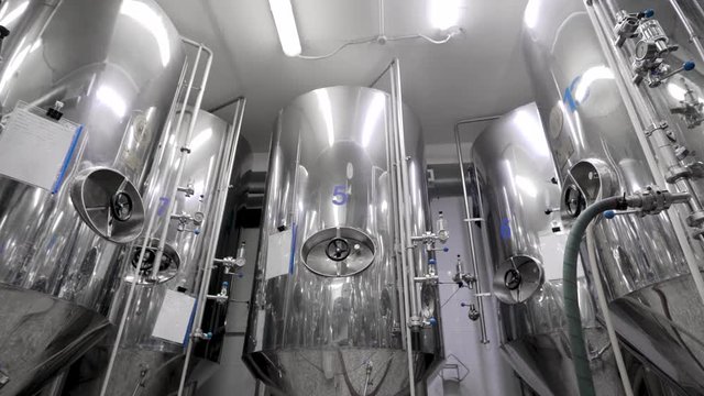 metal cisterns for mashing malt for beer are standing in shop of industrial brewery, round panoramic view