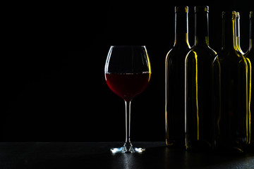 Bottles of wine and different glasses of wine on a dark background