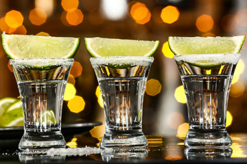 Shots of tequila on table against defocused lights