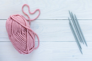Pink skein with gray needles isolated on white wooden background, knitting mittens or socks on 5 knitting needles