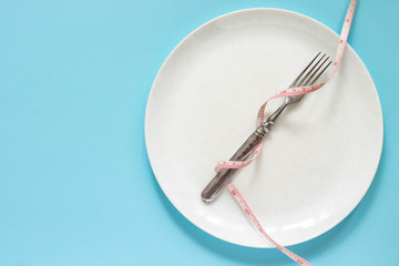 Diet concept. Fork on a white plate with centimeter. Time to lose weight , eating control or time to diet concept.