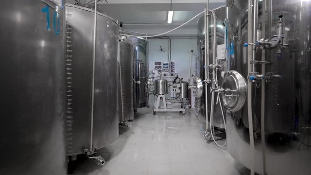 fermentation vats are standing in clean shop of modern brewery in working day, camera is moving back