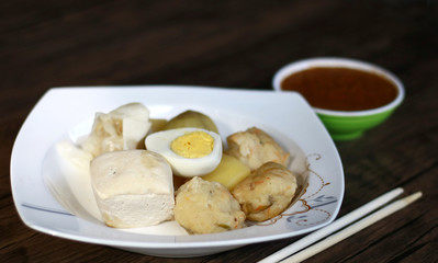 Siomay (fish cake dumplings) and peanut sauce on wood background. 