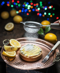 Lemon tart. Cooking of lemon dessert. Blurred festive background.
