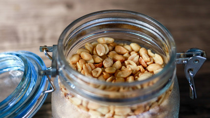 Fried peanuts in a jar on wood background.