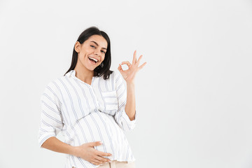 Photo of happy pregnant woman 30s with big belly smiling and showing ok sign