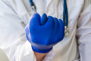 Doctor showing fig sign closeup. Doctor, scientist or researcher in a white lab coat and blue gloves demonstrated fig sign, folding fingers of palms to corresponding figure in the foreground