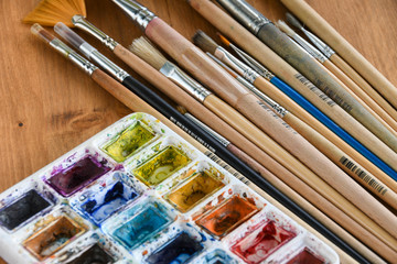 Obraz premium Colorful watercolor, acrylic paints and set of different brushes on wooden boards, closeup.