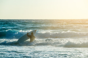 Young man, beginner Surfer learns to surf on a sea foam on the Crete island, beach Falasarna