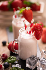 Glass of strawberry smoothie on wooden background