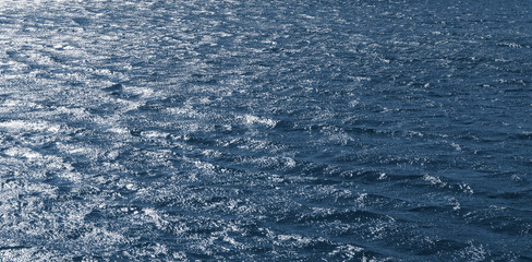 Background, texture from dark waves, in which the sun reflects. Dark waves on the surface of the...