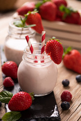 Glass of strawberry smoothie on wooden background