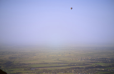 Fototapeta na wymiar Hot air balloon above the green field and villages