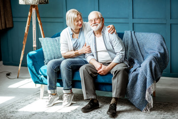 Lovely senior couple dressed casually having fun, sitting together on the couch at home