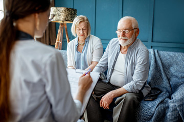 Obraz premium Senior couple sitting with nurse during the medical consultation in the comfortable office