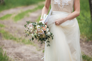 bride with a bouquet walks in the woods