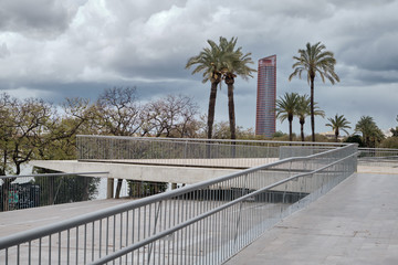 View along the river in Seville with modern Tower and palms on the background in a cloudy day.